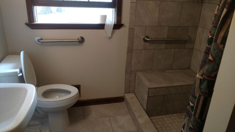 Bathroom with walk-in tiled shower and safety bars - Thaxton Roofing