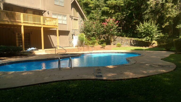 Backyard view of a newly built elevated wooden deck overlooking a swimming pool, completed by Thaxton Construction in Griffin, GA.