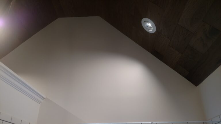 Bathroom with vaulted ceiling and recessed lighting, featuring dark wood ceiling panels and clean white walls, finished by Thaxton Construction in Griffin, GA.