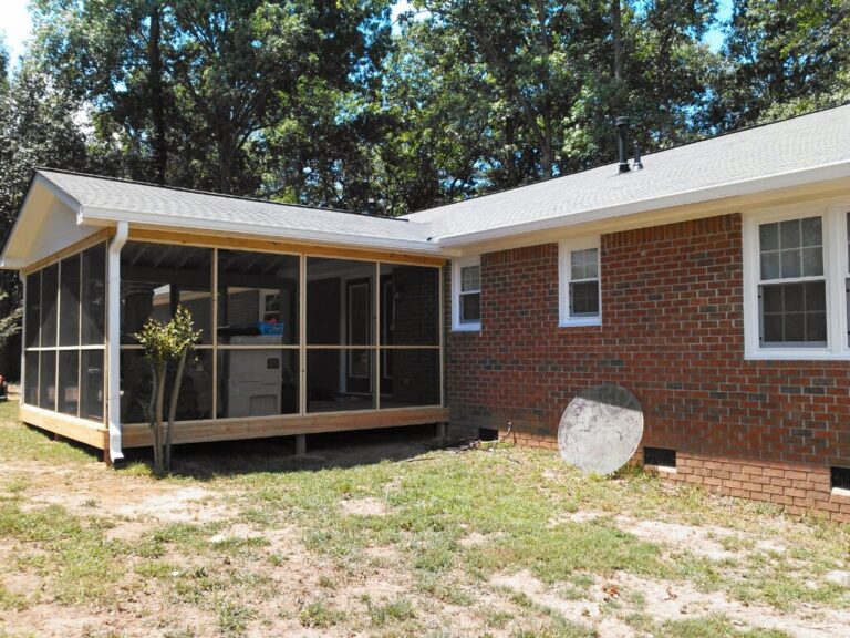 A brick residential house with a prominent screened-in porch on the left side, featuring a visible residential roofing structure and a well-maintained lawn.