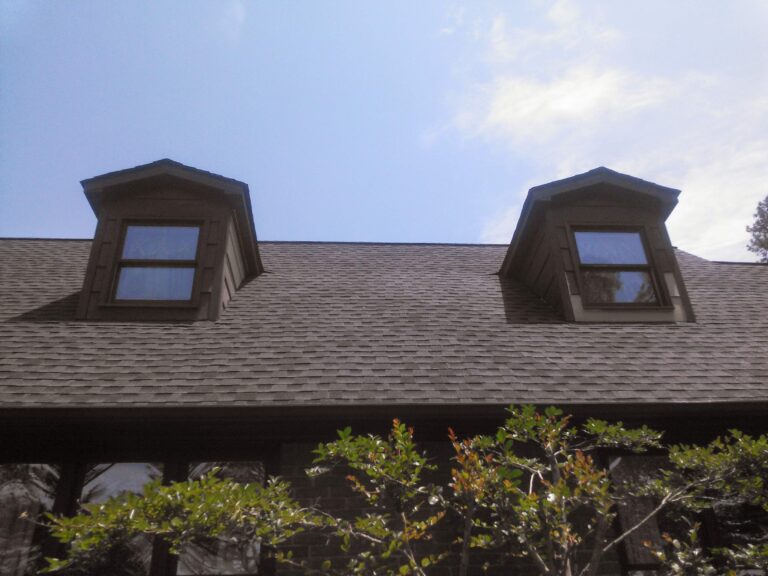 close-up view of a dark gray shingled roof with two dormer windows