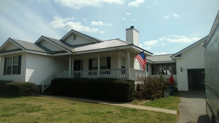 A white residential house with a gray metal residential roofing
