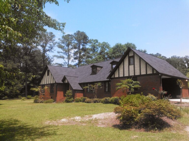 A classic brick house with a newly installed dark gray asphalt shingle roof
